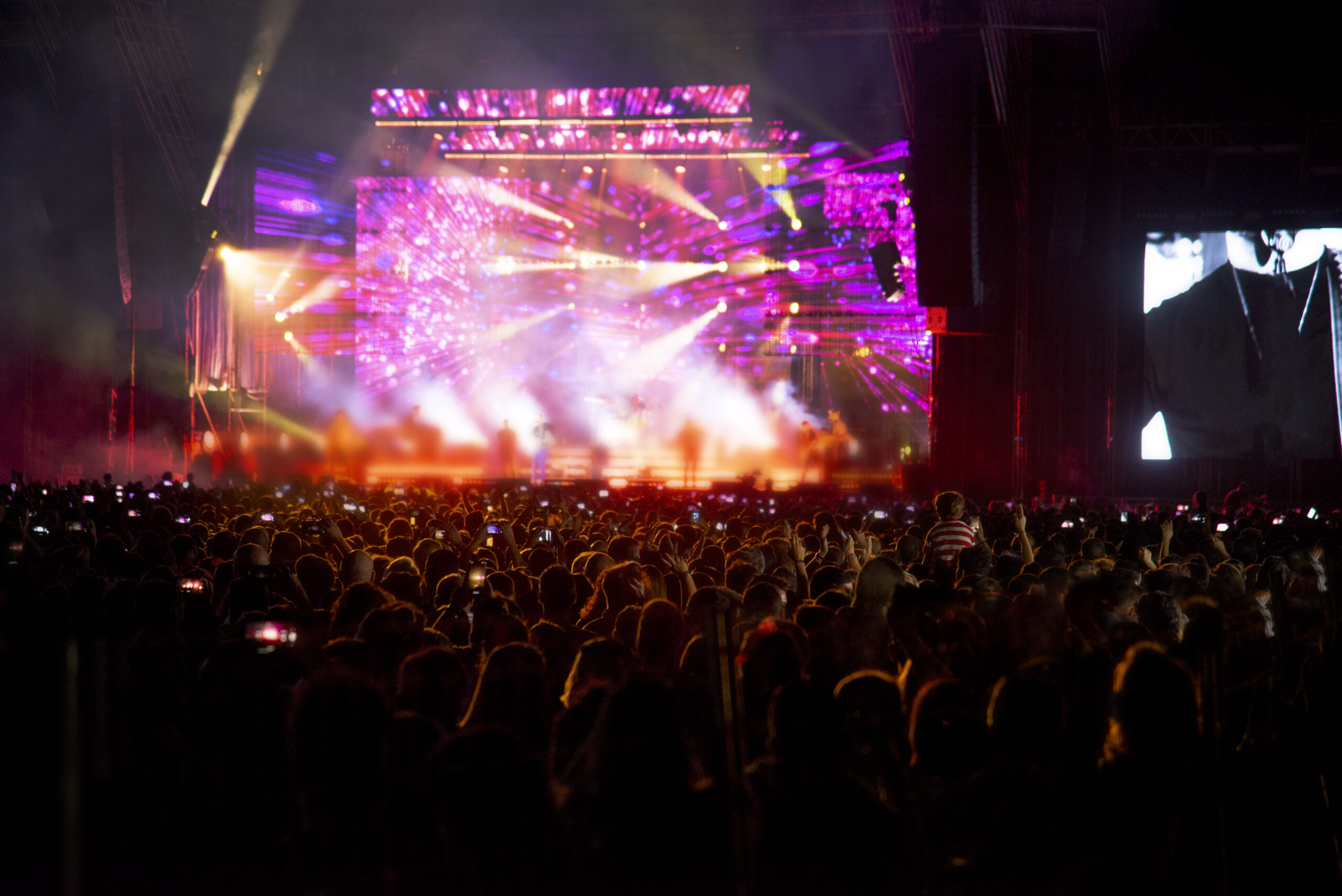 Silhouettes of concert crowd in front of bright stage lights